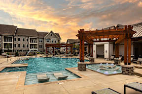 A large outdoor swimming pool with a wooden pergola and lounge chairs.
