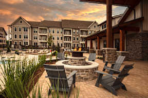 A fire pit sits in the middle of a patio surrounded by chairs.