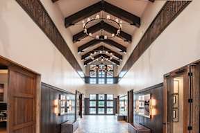 A long hallway with wooden doors and a chandelier hanging from the ceiling.