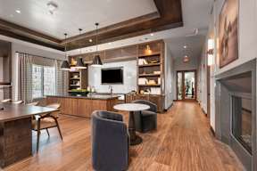 A modern kitchen with a long wooden table and grey chairs.