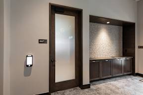 A modern door with a glass panel and a smart lock on the wall.