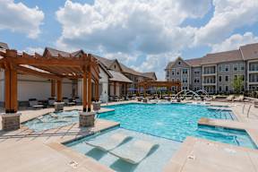 A large outdoor swimming pool with a wooden pergola.