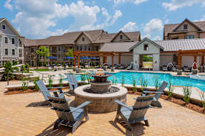 A pool area with a fire pit and lounge chairs.