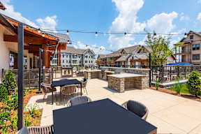 A patio with tables and chairs is surrounded by buildings.