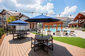 A wooden deck with a table and chairs overlooking a pool.