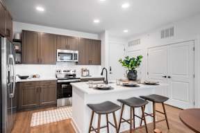 A modern kitchen with a white island and dark brown bar stools.