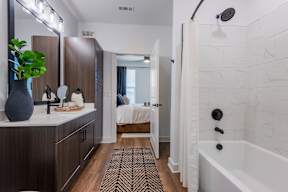 A bathroom with a white tub and a black and white rug.