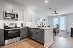 A modern kitchen with dark grey cabinets and stainless steel appliances.
