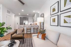 A modern living room with a grey couch and a dining table in the background.