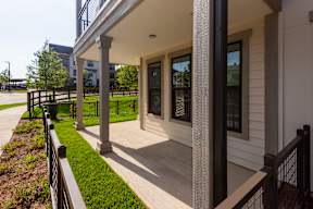 A white building with a black railing and a green lawn.
