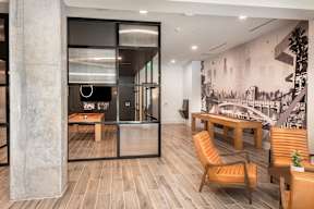 A modern office space with a wooden floor, a large mural on the wall, and a glass partition.