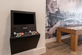 A black arcade machine sits on a wooden shelf.