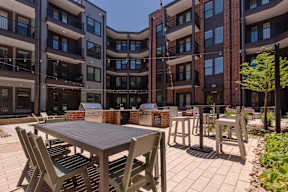 A table and chairs are set up on a patio in front of a brick building.