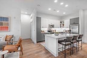 A modern kitchen with a white island and bar stools.