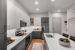 A modern kitchen with a white countertop and stainless steel appliances.