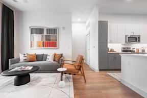 A modern living room with a grey couch, a wooden chair, and a coffee table.