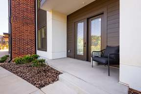 A black chair is on a patio next to a door.