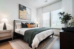 A bedroom with a large bed and a painting on the wall.