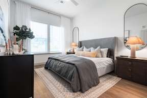 A bedroom with a large bed and a nightstand with a lamp.