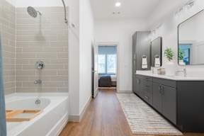 A modern bathroom with a white tub and wooden floors.