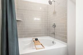 A white bathtub with a wooden tray and a shower head above it.
