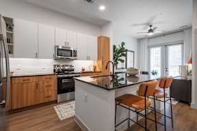 A kitchen with a refrigerator, microwave, oven, and sink.