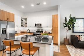 A modern kitchen with a refrigerator, sink, and two chairs.