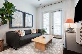 A black couch with pillows and a wooden coffee table in a room.
