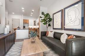 A living room with a couch, coffee table, and two framed artworks on the wall.