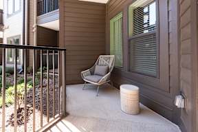 A chair is on a patio with a white container on the ground.