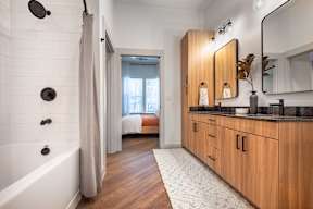 A bathroom with a white tub and wooden cabinets.