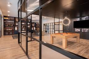 A room with a ping pong table and a bar area.