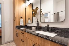 A bathroom with a large mirror and a vase with leaves on the counter.