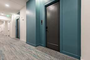 A hallway with a black door and a green wall.