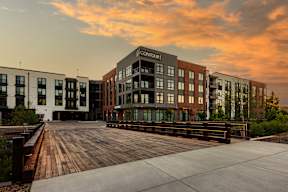 A modern building complex with a wooden walkway in front.