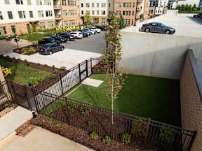 A parking lot with cars and a green space in front of a building.