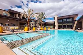 A large swimming pool in front of a building with palm trees.