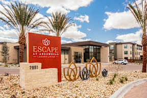 A sign for Escape at Arrowhead stands in front of a building.