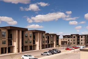 A row of apartment buildings with cars parked in front.