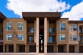 A modern building with a central entrance and balconies on the upper floors.