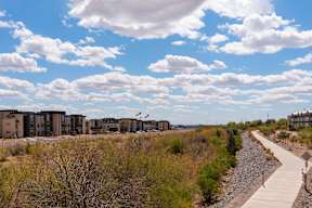 A pathway runs through a grassy area with a building in the background.
