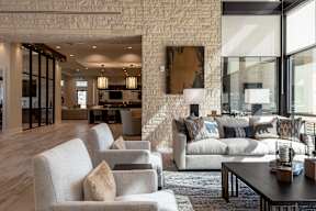 A living room with a white brick wall and a large abstract painting above a sofa.