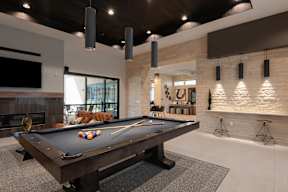 A pool table is in the middle of a room with a fireplace and a TV.
