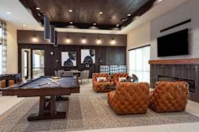 A pool table is in the middle of a room with a couch and ottoman.