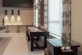 A room with a shiny black counter and a long wooden table.