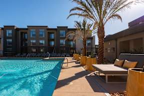 A pool area with sun loungers and palm trees.