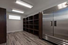A walk-in closet with a wooden floor and a metal door.