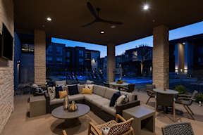 A patio with a couch, chairs, and a table with a fan.