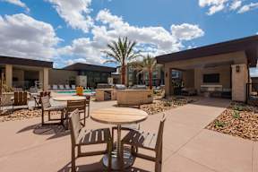 A patio with a table and chairs overlooking a pool.
