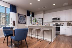A blue chair sits in a kitchen with a white island and a fridge.